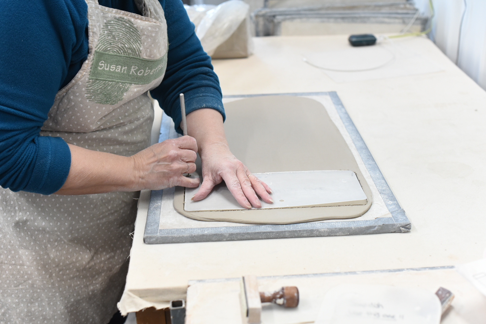 Hands cutting clay around a plastic template